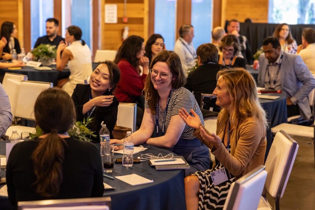 Tables of attendees at the Leadership Connect Global Summit laugh and talk amongst themselves.