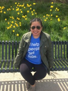 woman smiling sitting on park bench with yellow flowers in the background