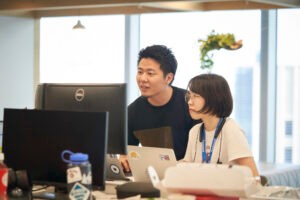 Taikai and co-worker have a discussion desk-side