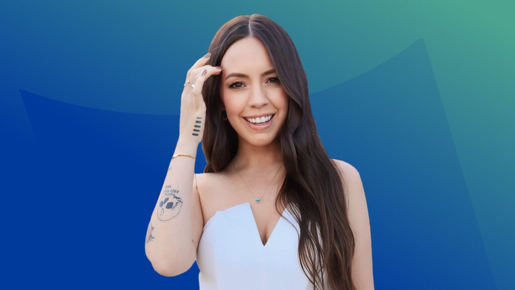 A smiling image of Dr. Courtney Tracy, a millennial white woman with long brunette hair, brown eyes and several tattoos on her arms.