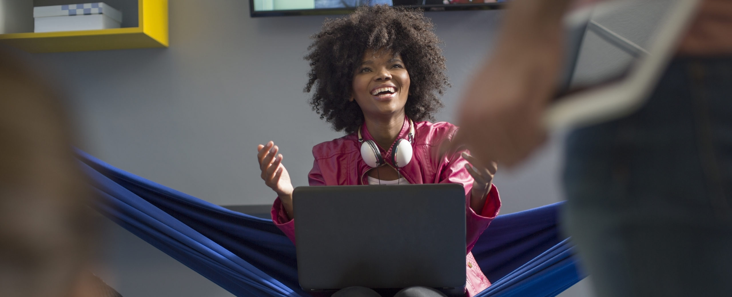 Femme souriante assise avec son ordinateur portable sur un hamac