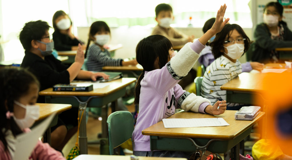 授業で手をあげている女子生徒