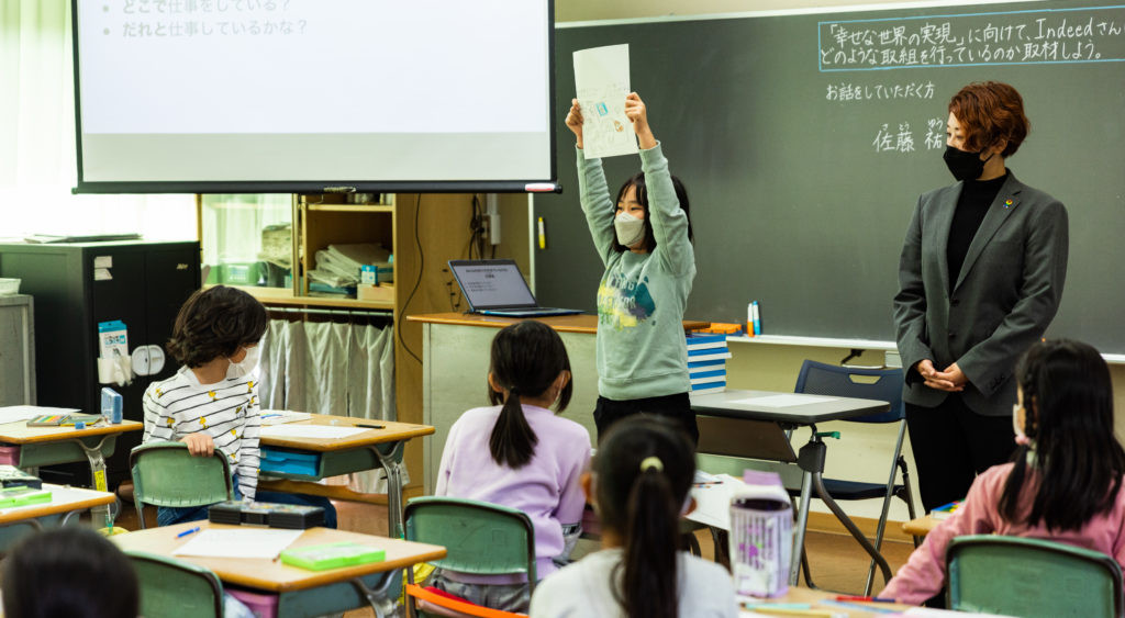 教室の前に立って自分が描いた職場について発表する女子生徒