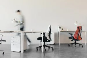 Two empty work desks with a blurred person walking away from them