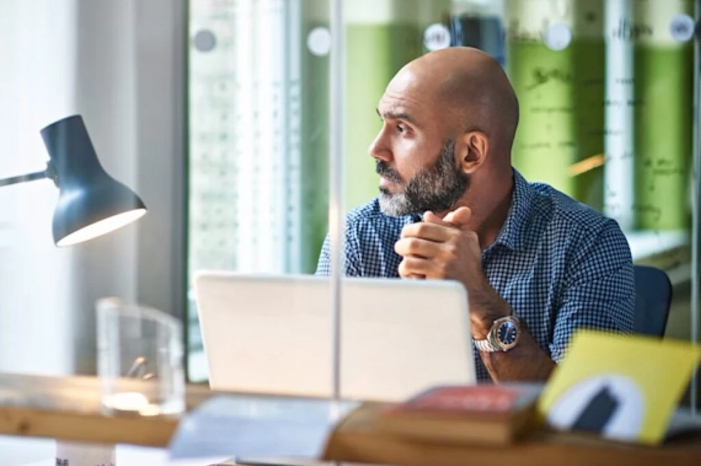 man working at desk looking out window