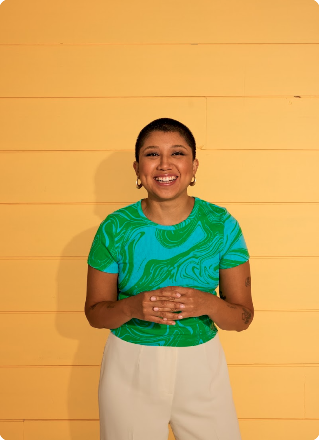 Smiling woman in front of a yellow wall. 