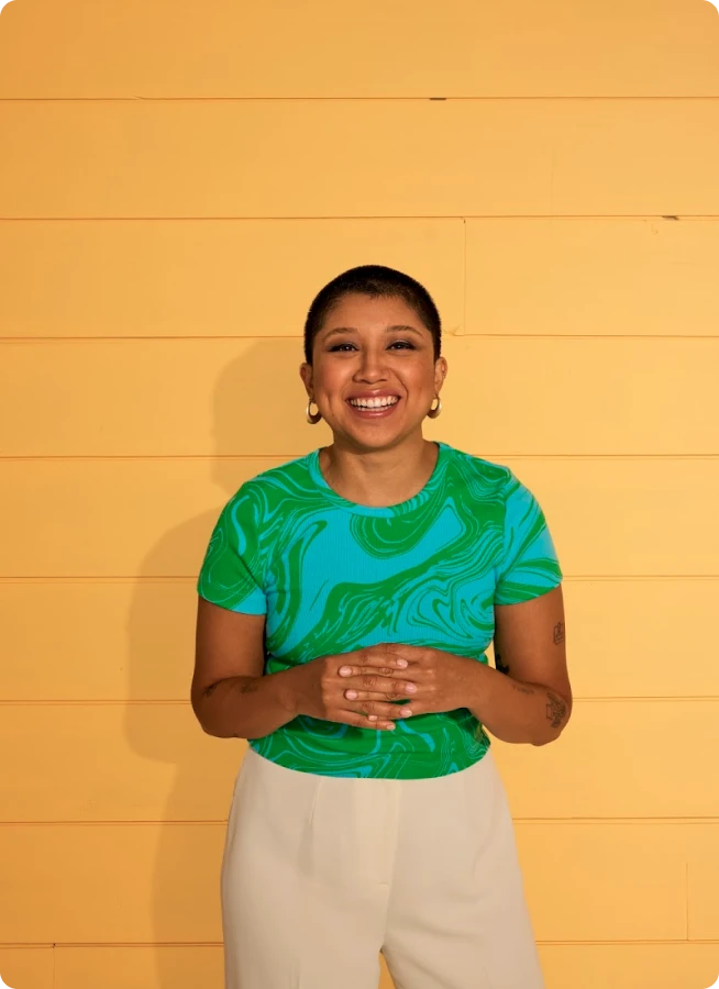Smiling woman in front of a yellow wall. 