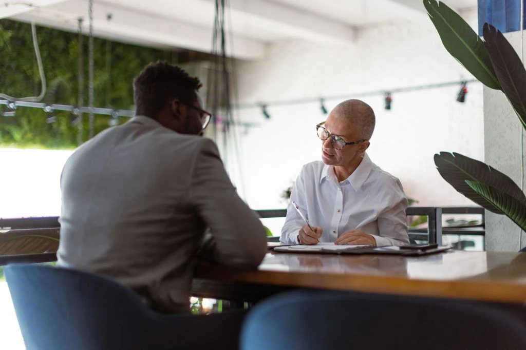 Two people having a conversation across an office desk.