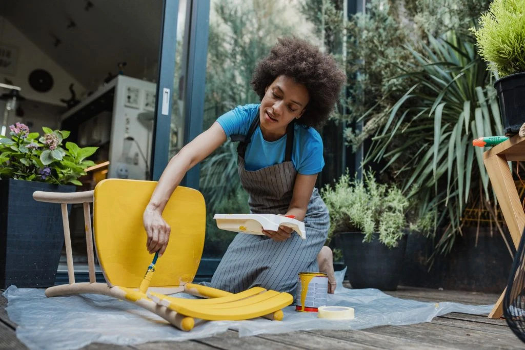Woman painting a chair outside her studio.