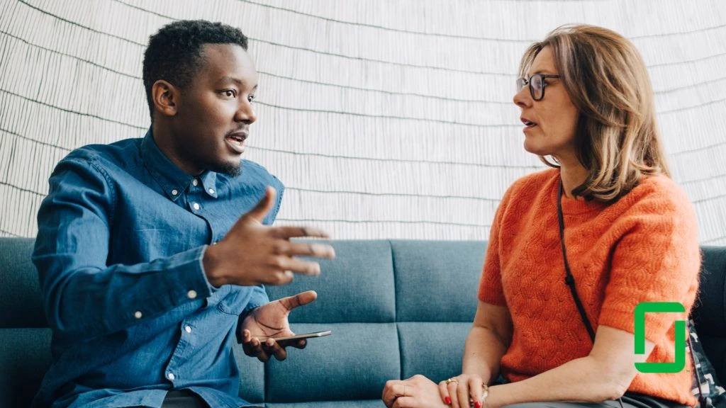 Two people seated on sofa having a conversation