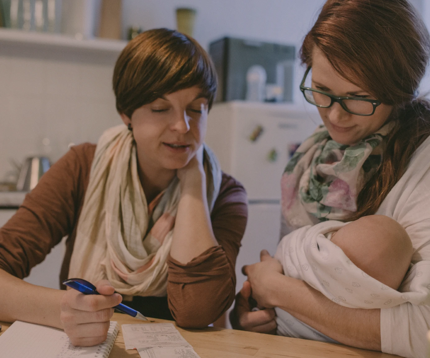 Women talking with mom holding baby and reviewing papers