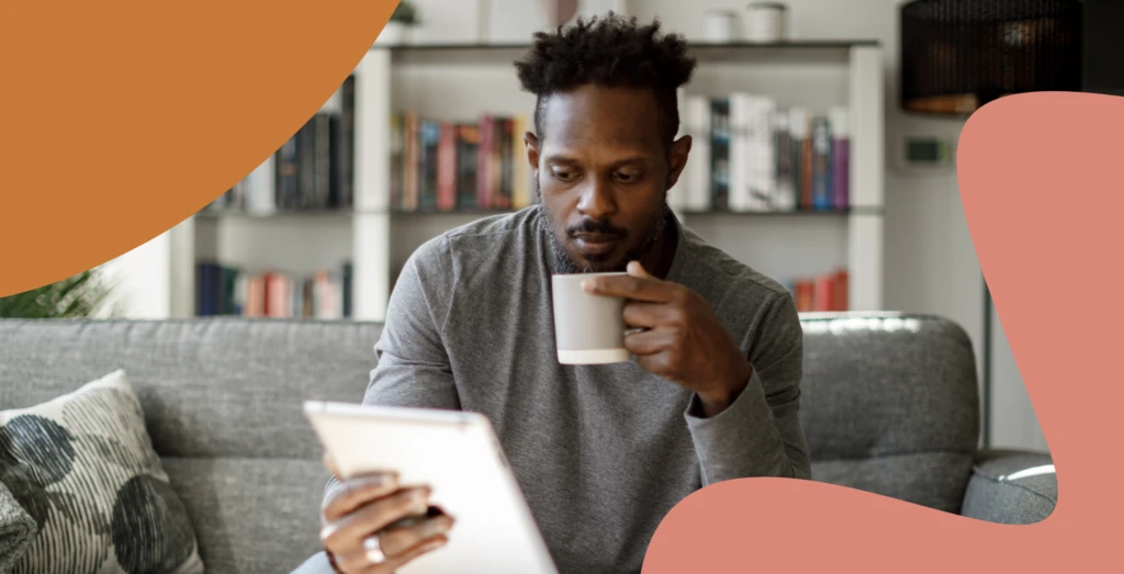 Man looking at a tablet and drinking coffee