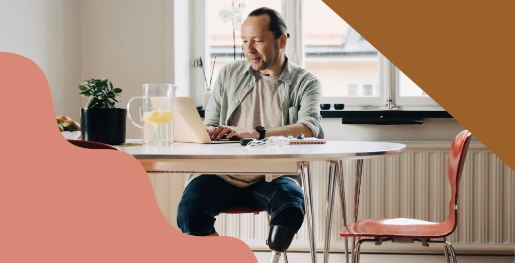 Man sitting at kitchen table working on computer