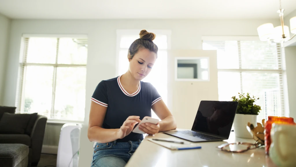 Caucasian woman sitting at a desk looking at her phone.