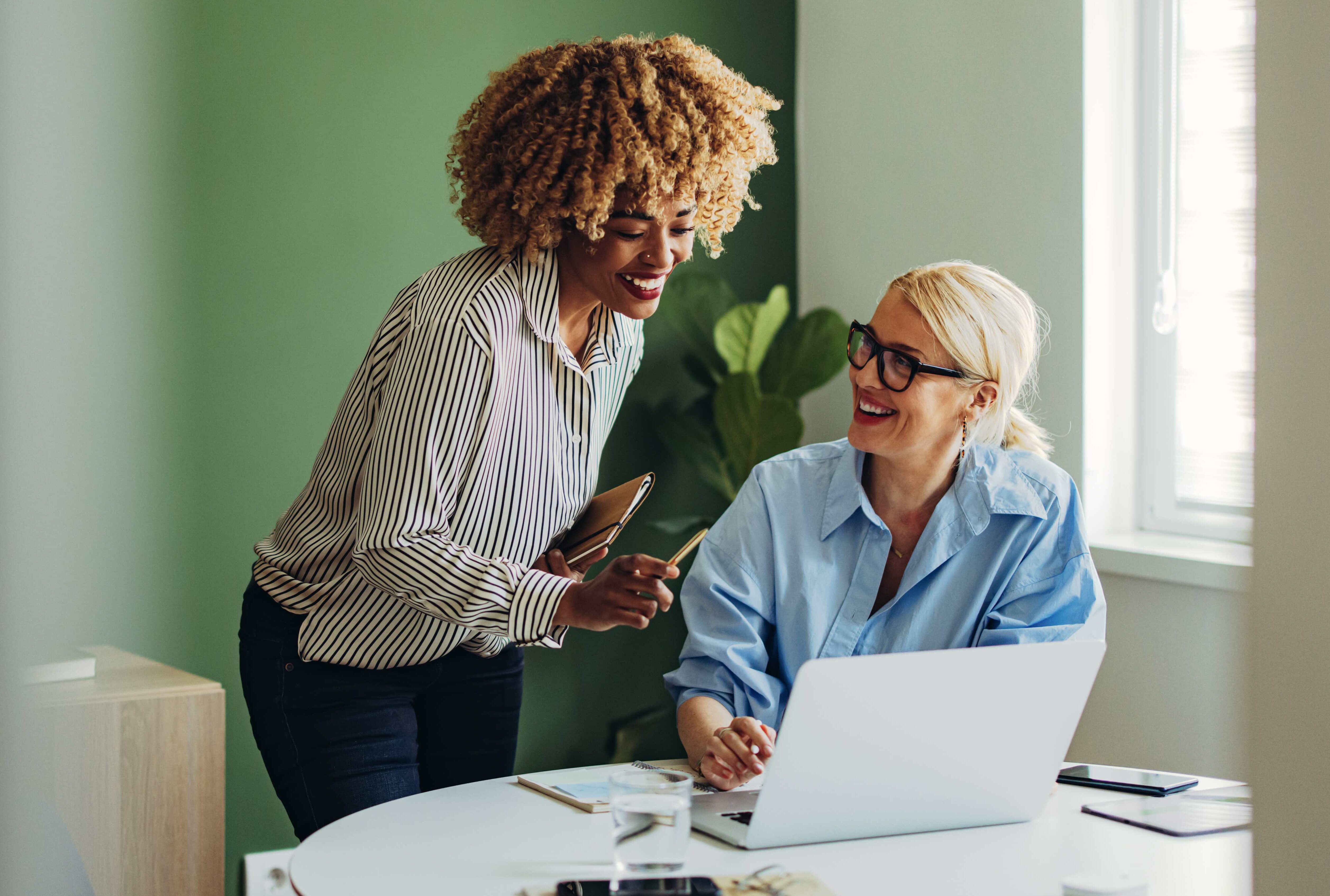 Team Of Two Happy Businesswoman Working Together on a Laptop Computer