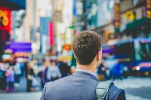 Photo of back of shoulders and head of a man with a busy city blurred in the background