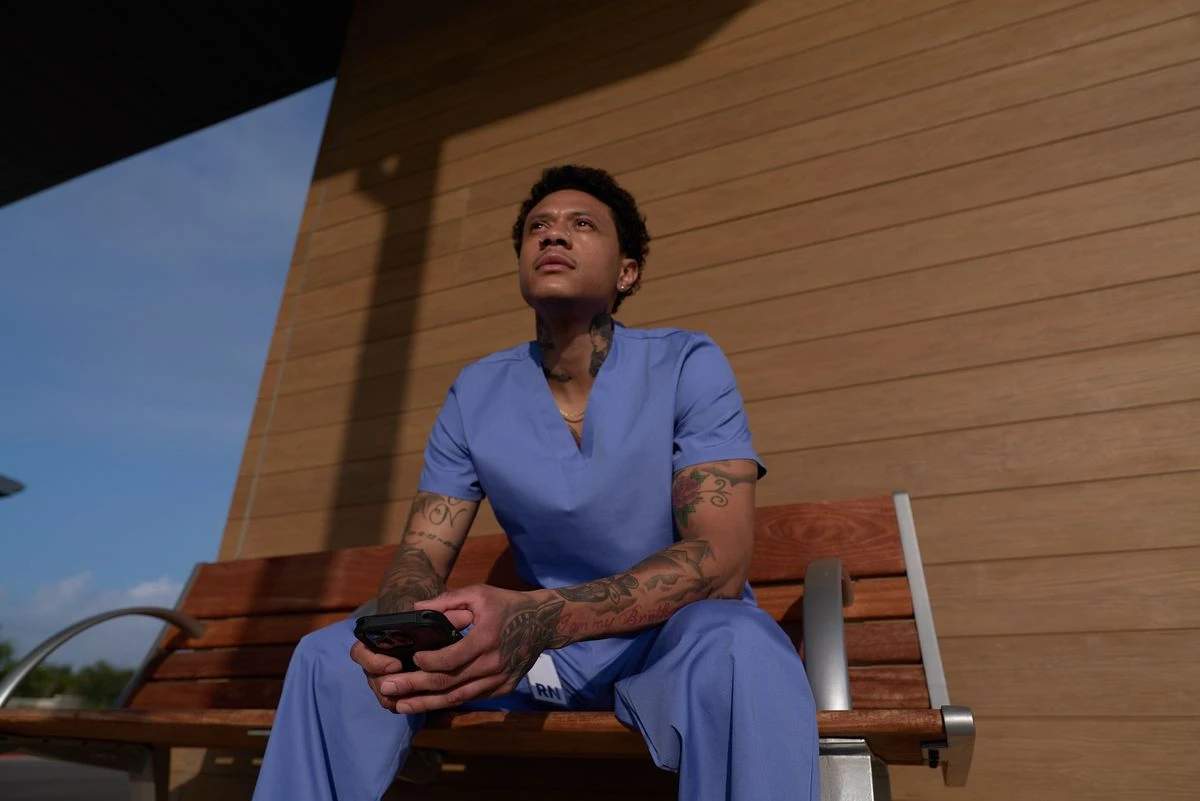 Nurse in blue scrubs sitting on bench