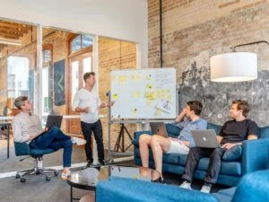 a group of people reviewing sticky notes on a whiteboard