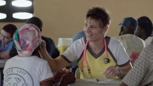A female health professional sitting with a patient in a community setting.