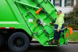 Garbage collector on truck driving along street