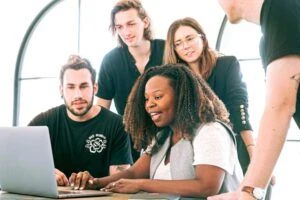 A group of young professionals collaborating and working on a laptop