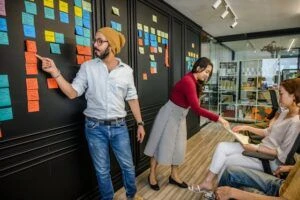 A team collaborating together during a meeting and reviewing colorful sticky notes on a wall