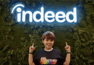 Jill posing in front of an Indeed sign