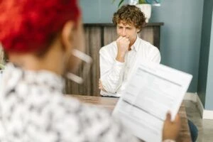 A candidate being interviewed by a woman holding a resume