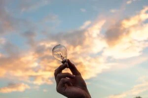 Holding a light bulb against a sunsetting sky