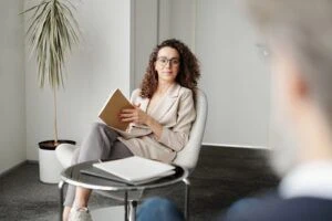 A confident woman leaning back in her chair while interviewing a candidate.