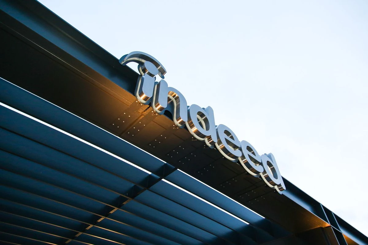 Signage displaying the Indeed logo mounted on a building façade under a blue sky