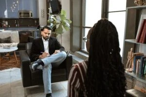 An interviewer taking notes while a job candidate talks about their experience