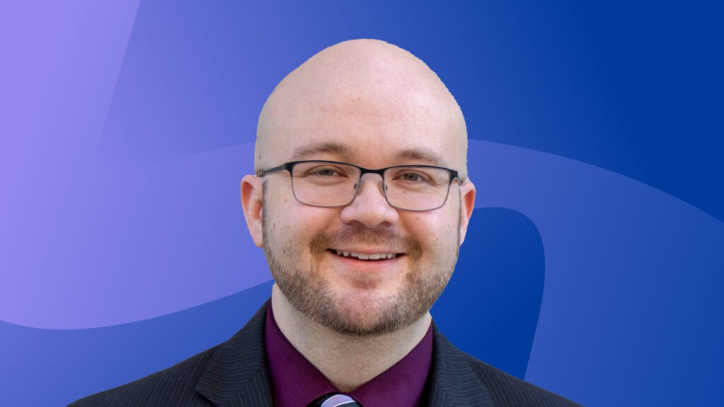 Portrait of Cory Stahle, Indeed Hiring Lab Economist focused on the U.S. labor market, in front of a colorful background.