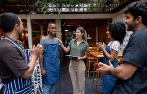 Happy business manager introducing a new employee at a restaurant while the rest of the team is applauding