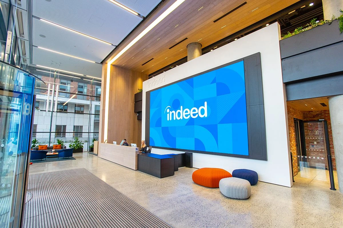 Indeed Dublin reception area features a large blue screen displaying the Indeed logo in white, with abstract blue shapes in the background