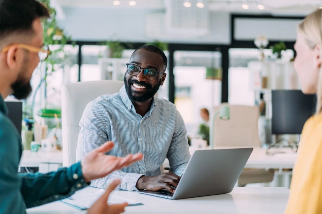 2 men speaking with eachother office setting, smiling.