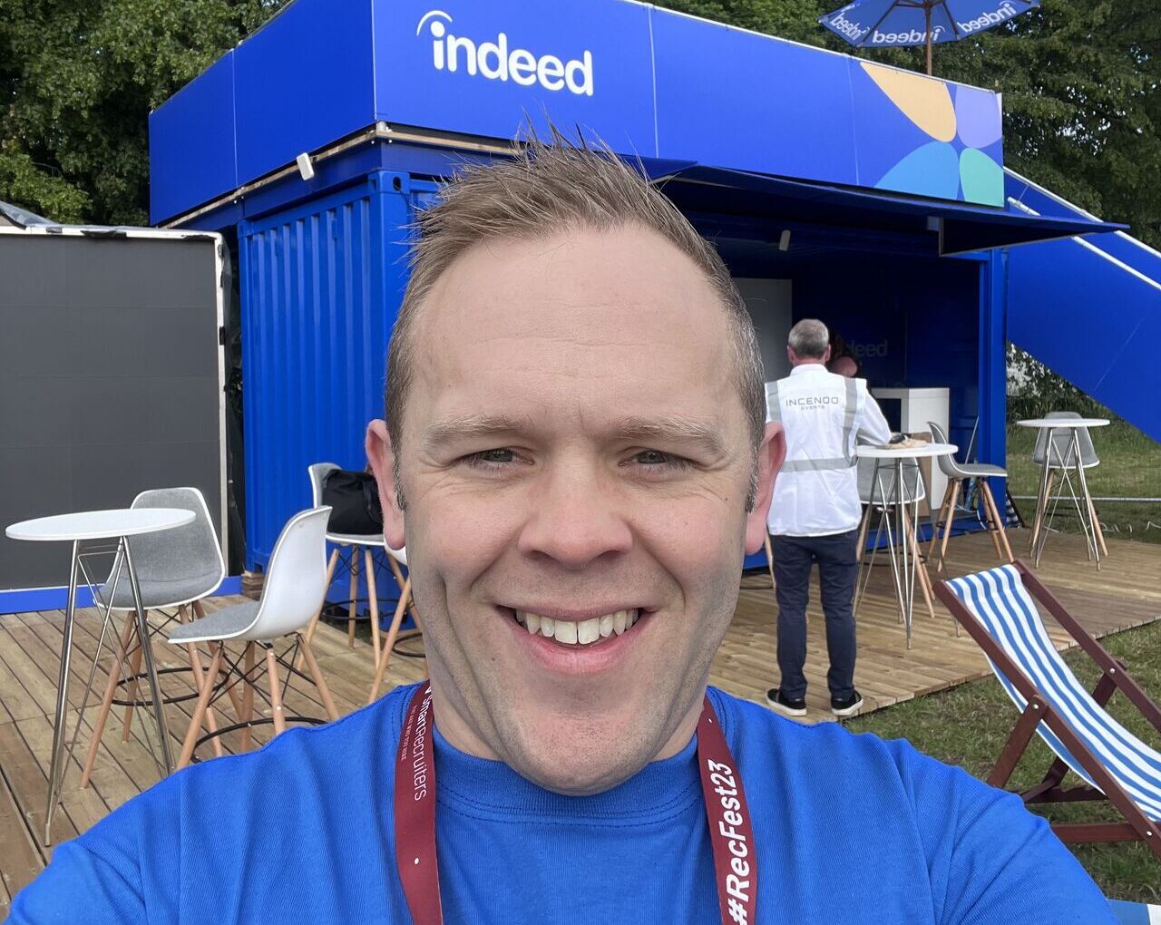 Oliver in a blue shirt in front of an Indeed-branded booth