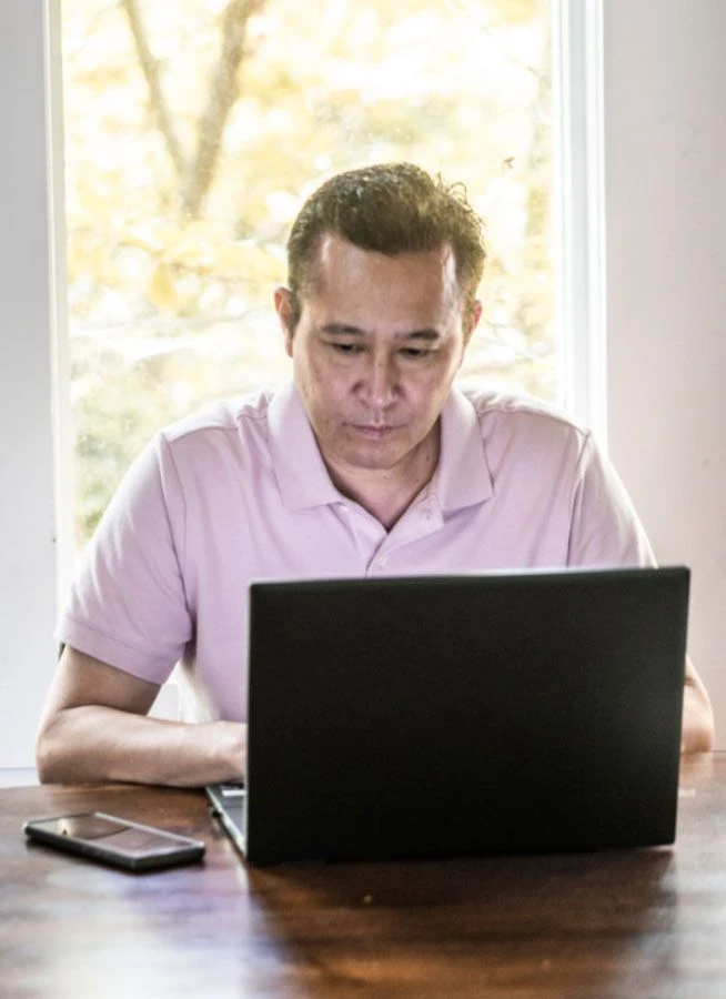 Man sitting at table typing on his laptop