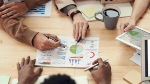 close up of hands pointing at a chart in the middle of a table
