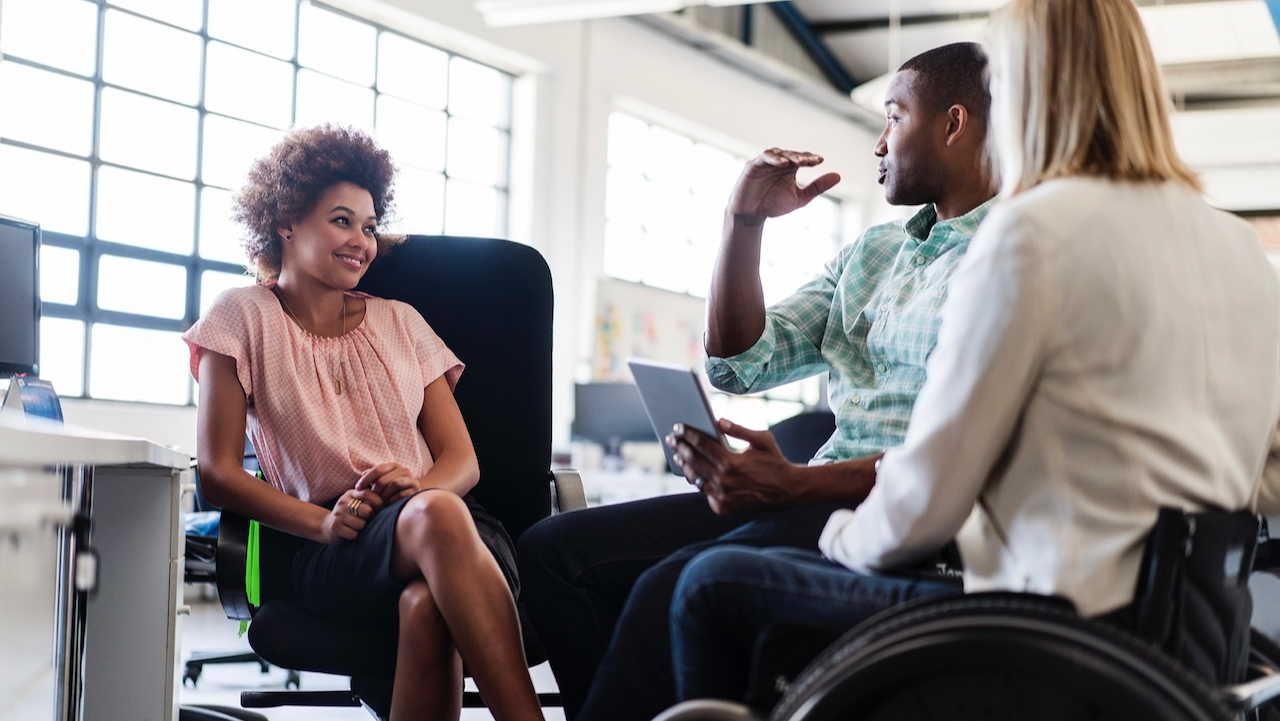 Woman sitting on a chair talking to her colleagues