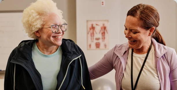 Female healthcare worker in purple jacket assisting elderly woman