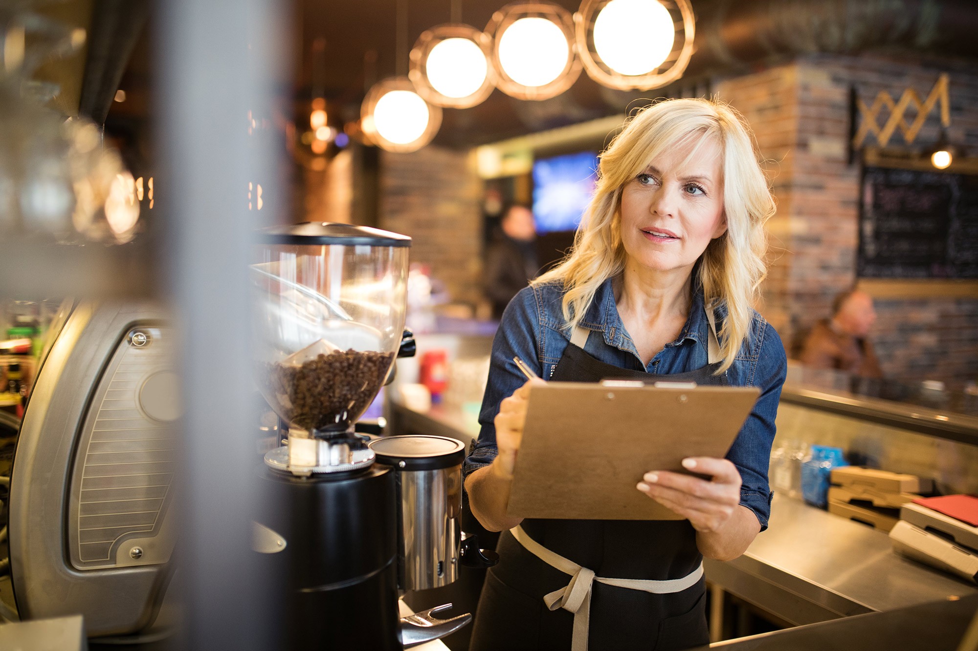 A mature woman in a coffee shop taking notes