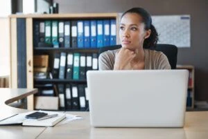Contemplative woman working and thinking at her laptop