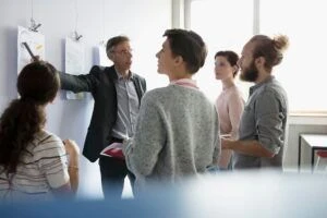 Professor and mature students discussing diagrams in classroom