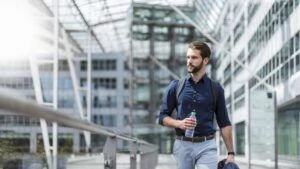 Man outside by building holding water bottle