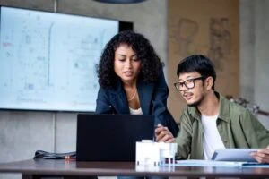 Sustainability in Design and Construction to Achieve Operational Efficiency, Reduce Environmental Impact, and a Smart Investment. A construction project manager and designer on construction design discussion via a laptop computer in an architect's office.