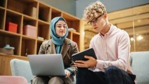 Two colleagues smiling and discussing work in a colorful office