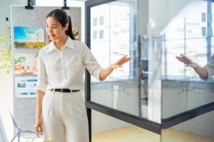 A woman giving a presentation in a glass office