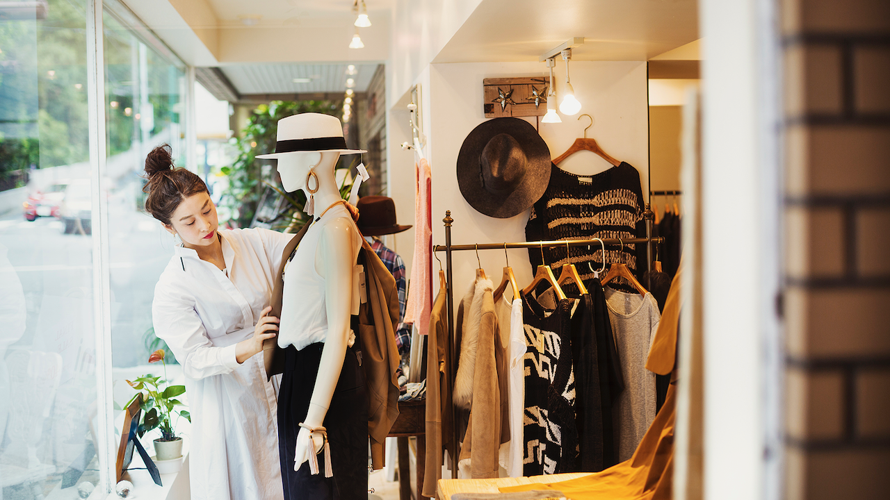A woman fixing a mannequin in a clothing store