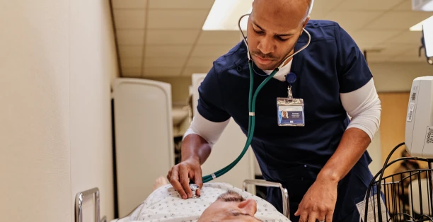 Un infirmier analyse les battements du cœur d'un patient à l'aide d'un stéthoscope.
